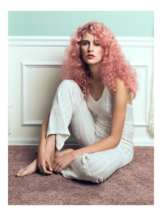 Ford model Jordan Strange sitting on floor with curly pink hair wearing a white knit For Love and Lemons jumpsuit photographed by Joshua Pyles