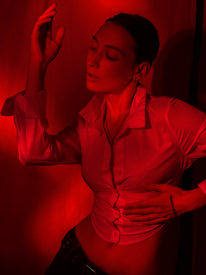 Red monochrome image of model Tehya McDonald posing in a sheer white blouse and short shorts photographed by Joshua Pyles